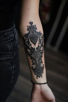 a woman's arm with a black and white tattoo design on her left arm