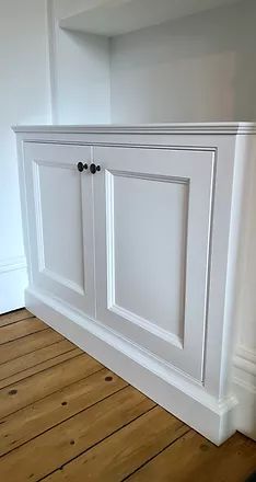 an empty room with white cabinets and wood flooring