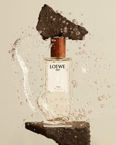 an image of a bottle in the air with water splashing around it and on top of a rock