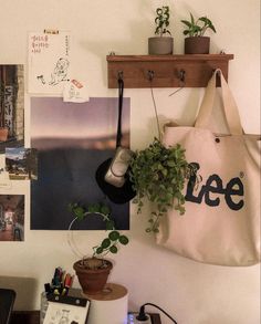 a bag hanging on the wall next to a potted plant and other office supplies