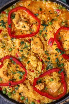 a pan filled with rice and chicken covered in red peppers, garnished with parsley