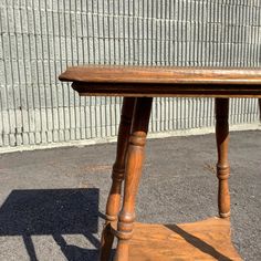 an old wooden table sitting in front of a brick wall with a shadow cast on it