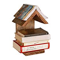 a stack of books sitting on top of each other next to a wooden bird house