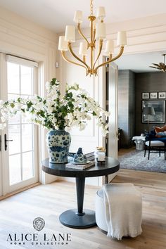 a vase with white flowers sitting on top of a table next to a chair in a living room