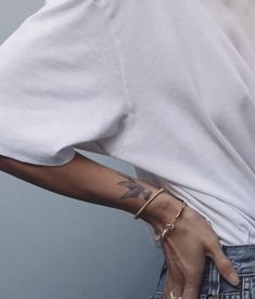 a woman with tattoos on her arm wearing jeans and a white t - shirt is posing for the camera