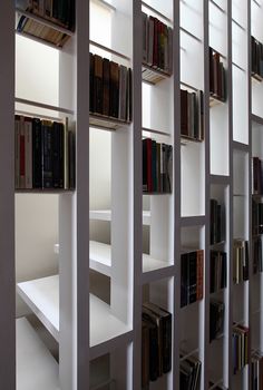 the bookshelves are filled with many different types of books in white painted shelves