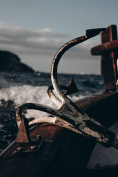 an old rusted boat in the water with a cross on it's side