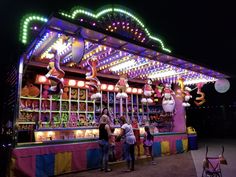 people standing in front of a carnival booth at night