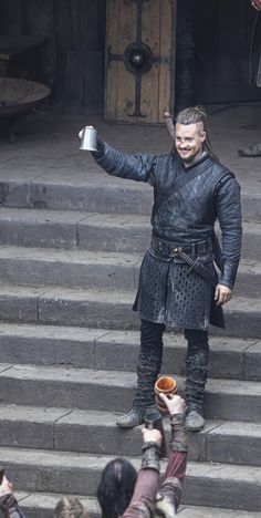 a man dressed in black is standing on some steps with his arms out to the crowd