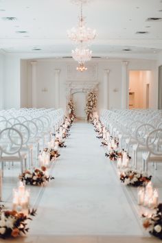 the aisle is lined with white chairs and candles