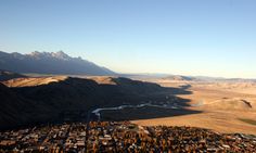 an aerial view of a city surrounded by mountains in the distance with a river running through it