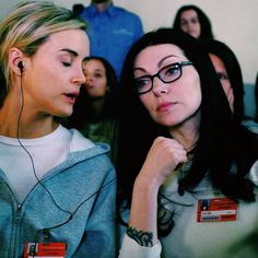 two women are looking at each other in front of a group of people wearing headphones