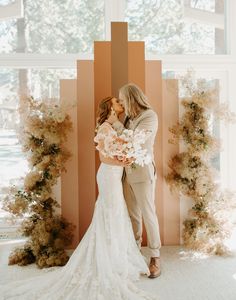 a bride and groom kissing in front of an artistic backdrop