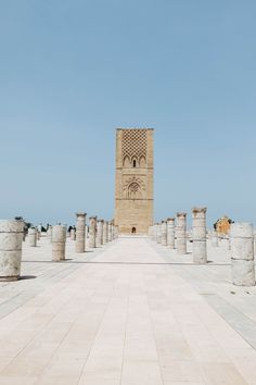 an empty walkway with columns and a clock tower in the background