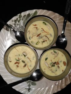 three bowls of soup on a plate with spoons