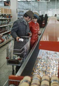 an older man and young boy are shopping in a grocery store with their cart full of items