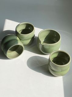 four green bowls sitting on top of a white table