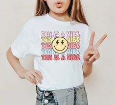 Celebrate her 10th birthday with this groovy TEN is a vibe birthday shirt. ..♥..Unisex fit Jersey Short-Sleeve T-Shirt..♥.. Available sizes: YOUTH: S(6/8) M(10/12) L(14/16) XL (18) ADULT: S M D E T A I L S Pre-shrunk fabric Solid Colors: 100% combed and ring-spun cotton Heather Colors: 52% ring-spun cotton, 48% polyester Athletic and Black Heather: 90% ring-spun cotton, 10% polyester This is a direct to garment print, no vinyl or stencils. PRODUCTION & SHIPPING - Please allow 2-10 business days for your order to be processed and made - Standard shipping takes 3-5 days - Please note that these times are estimated by USPS and may take longer - Please make sure your shipping address is correct before placing an order - Printed and Shipped in the USA Machine wash cold, inside-out, gentle cycle Ten Is A Vibe Birthday, 10th Birthday Girl, 10th Birthday Shirt, Girls Birthday Shirt, Tie Dye Birthday, Girl Bday Party, Birthday Words, 10th Birthday Parties, Bday Girl