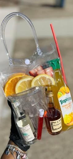 a person holding a plastic bag full of drinks and condiments in their hands