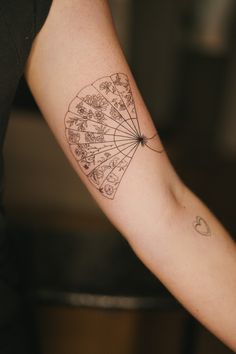 a person with a tattoo on their arm holding an umbrella in one hand and writing on the other