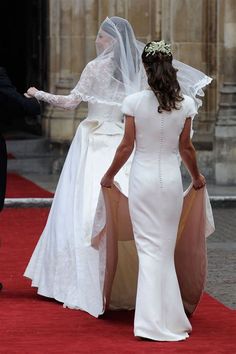 the bride is walking down the red carpet with her veil draped over her head and she is wearing a white wedding gown