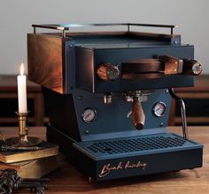 an espresso machine sitting on top of a wooden table next to a lit candle