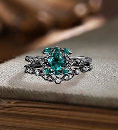 an emerald colored ring sitting on top of a book