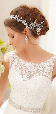 a woman wearing a wedding dress with white flowers in her hair and an elegant headpiece