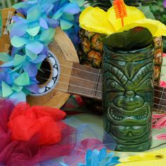 a ukulele, pineapple and flower arrangement on a table with tulle