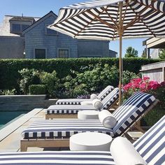 lounge chairs and umbrellas are lined up on the patio next to an outdoor swimming pool