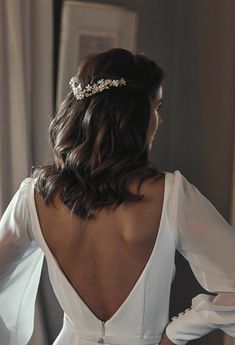 the back of a woman wearing a white dress with long sleeves and a beaded headpiece