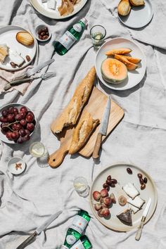 an assortment of food is laid out on a table with plates and utensils