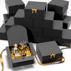 several black boxes with gold bows and bottles in them