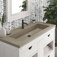 a bathroom sink sitting under a mirror next to a plant