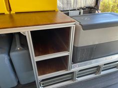 an old tv sitting on top of a wooden table next to blue containers and yellow bins