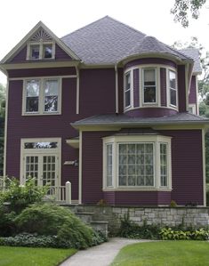 a purple house with white trim and two story windows on the second floor is shown