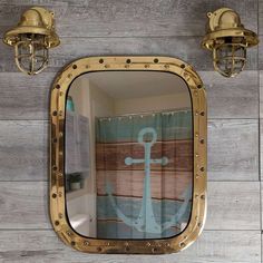 a mirror with an anchor on it is hanging on the wall next to two lights