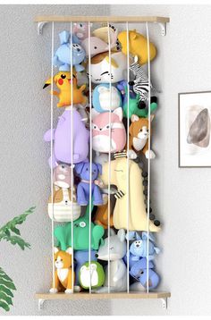 a bunch of stuffed animals in a cage on a shelf next to a plant and pictures