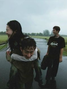 three people are walking down the street with one person covering his face from the rain