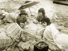 three women laying on the sand with an umbrella