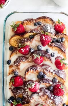 a dessert with strawberries and blueberries on top is in a glass baking dish