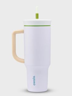 a white coffee cup with a green lid and handle on the side, in front of a gray background