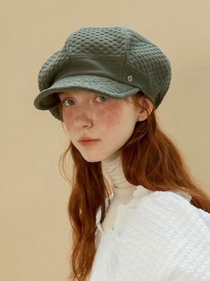 a woman with red hair wearing a green hat and white sweater is looking at the camera