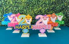 colorful paper cut out numbers with shark faces on them and the words happy birthday are displayed in front of a hedge