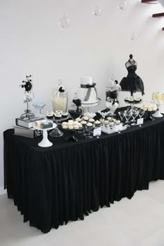 a black and white dessert table with cupcakes, cakes, and other treats