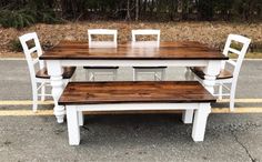 a white table and four chairs sitting on top of a wooden bench in the middle of a parking lot