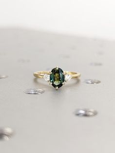 a green and white diamond ring sitting on top of a table