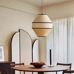 a dining room table and chairs in front of a large window with white drapes