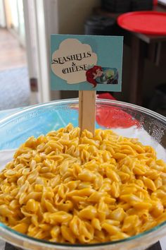 a glass bowl filled with macaroni and cheese sitting on top of a table