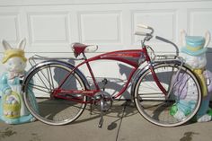 a red bicycle parked in front of a garage door with bunny statues on the side